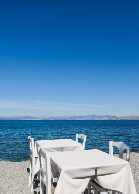 Beyaz Restoran tablolar sahilde yaz - seyahat, tatil ve yaz konsepti. Deniz manzaralı mükemmel bir öğle yemeği