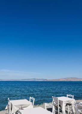 Beyaz Restoran tablolar sahilde yaz - seyahat, tatil ve yaz konsepti. Deniz manzaralı mükemmel bir öğle yemeği