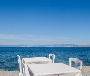 Beyaz Restoran tablolar sahilde yaz - seyahat, tatil ve yaz konsepti. Deniz manzaralı mükemmel bir öğle yemeği
