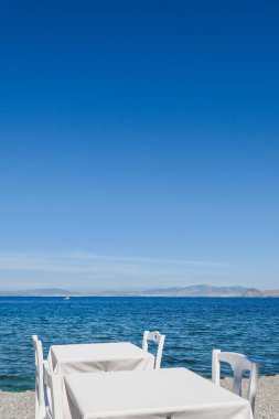 Beyaz Restoran tablolar sahilde yaz - seyahat, tatil ve yaz konsepti. Deniz manzaralı mükemmel bir öğle yemeği