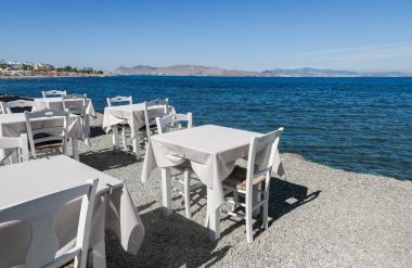 Beyaz Restoran tablolar sahilde yaz - seyahat, tatil ve yaz konsepti. Deniz manzaralı mükemmel bir öğle yemeği