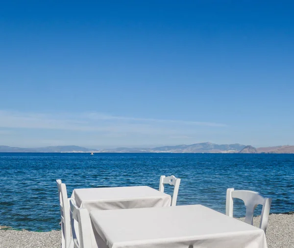 Beyaz Restoran tablolar sahilde yaz - seyahat, tatil ve yaz konsepti. Deniz manzaralı mükemmel bir öğle yemeği