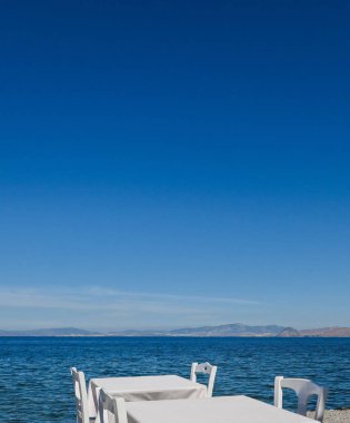 Beyaz Restoran tablolar sahilde yaz - seyahat, tatil ve yaz konsepti. Deniz manzaralı mükemmel bir öğle yemeği