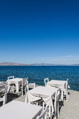 Beyaz Restoran tablolar sahilde yaz - seyahat, tatil ve yaz konsepti. Deniz manzaralı mükemmel bir öğle yemeği