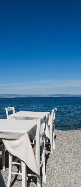 Beyaz Restoran tablolar sahilde yaz - seyahat, tatil ve yaz konsepti. Deniz manzaralı mükemmel bir öğle yemeği