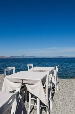 Beyaz Restoran tablolar sahilde yaz - seyahat, tatil ve yaz konsepti. Deniz manzaralı mükemmel bir öğle yemeği
