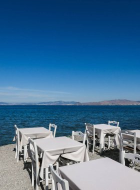Beyaz Restoran tablolar sahilde yaz - seyahat, tatil ve yaz konsepti. Deniz manzaralı mükemmel bir öğle yemeği