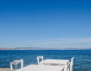 Beyaz Restoran tablolar sahilde yaz - seyahat, tatil ve yaz konsepti. Deniz manzaralı mükemmel bir öğle yemeği