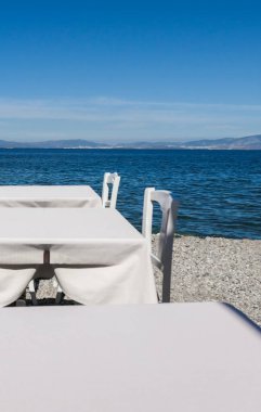 Beyaz Restoran tablolar sahilde yaz - seyahat, tatil ve yaz konsepti. Deniz manzaralı mükemmel bir öğle yemeği