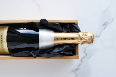 Şampanya şişesi ve mermer üzerinde bir hediye kutusu