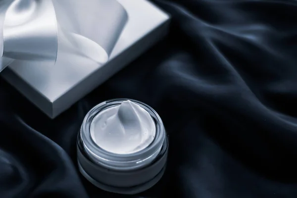 Luxury moisturizing cream and a gift box on black silk