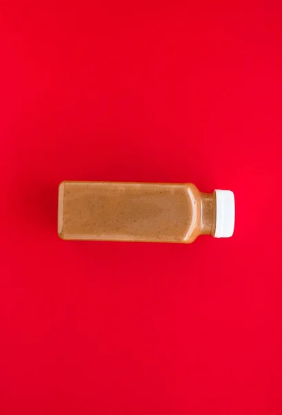 Chocolate banana smoothie bottle on red, flatlay — Stock Photo, Image