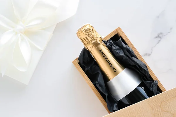 Eine Champagnerflasche und eine Geschenkbox auf Marmor — Stockfoto