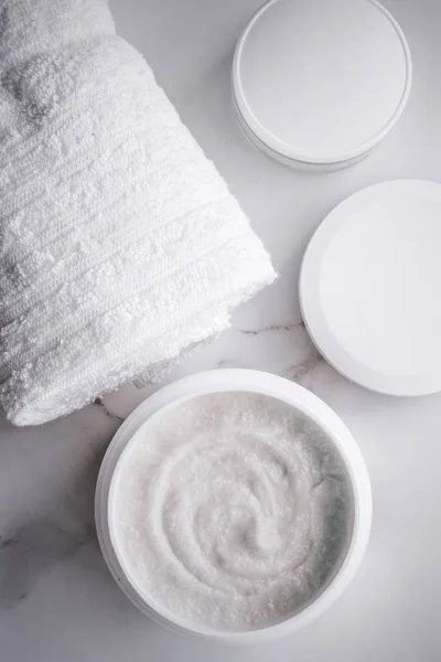 Scrub and exfoliating cream products on a marble, flatlay