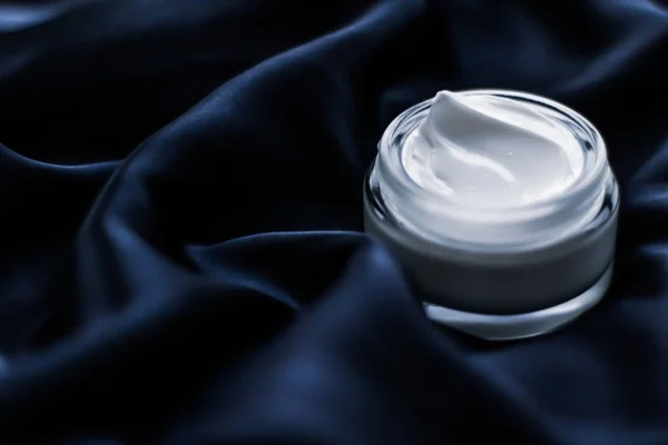Luxury face cream jar on a dark blue silk — Stock Photo, Image