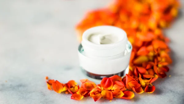 Crema hidratante de la cara de belleza y pétalos de flores en mármol, luxu — Foto de Stock