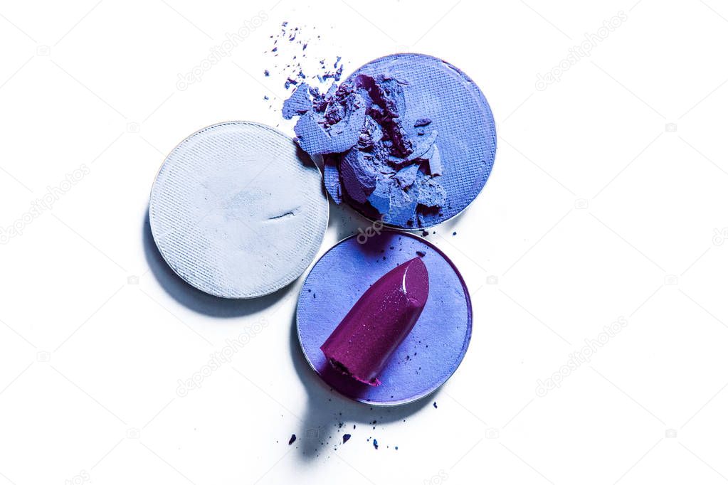 Crushed eyeshadows and lipstick isolated on white background