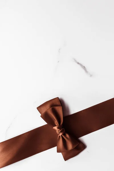 Čokoládová hnědá hedvábná stuha na mramorovém pozadí, ploché — Stock fotografie