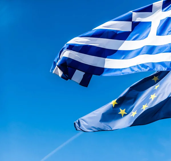 Flags of Greece and European Union on blue sky background, polit