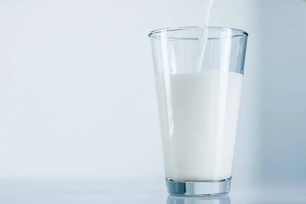 Παγκόσμια ημέρα γάλακτος, χύνοντας σε γυαλί σε μαρμάρινο τραπέζι — Φωτογραφία Αρχείου