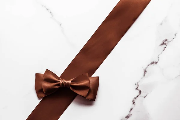 Cinta de seda marrón chocolate sobre fondo de mármol, plano — Foto de Stock