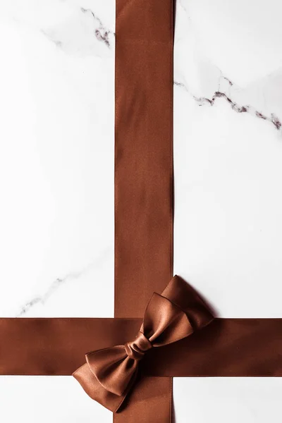 Cinta de seda marrón chocolate sobre fondo de mármol, plano —  Fotos de Stock