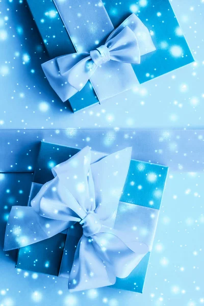 Winter holiday gifts and glowing snow on frozen blue background, — Stock Photo, Image