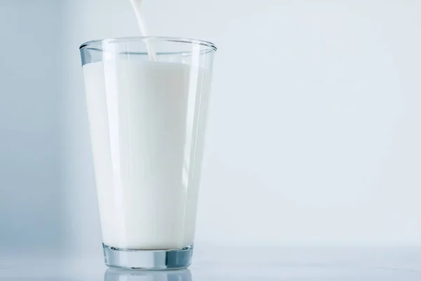Всемирный день молока, льющийся в стекло на мраморный стол — стоковое фото