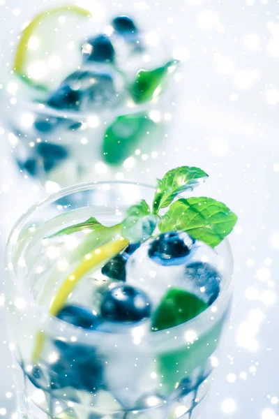 Winter holiday cocktail with ice and glowing snow on background,