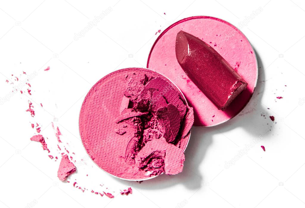 Crushed eyeshadows and lipstick isolated on white background