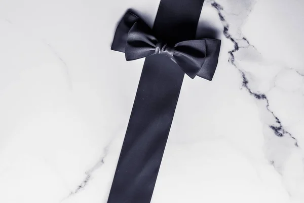 Black silk ribbon and bow on marble background, flatlay — Stock Photo, Image