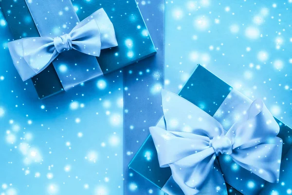 Χειμερινά δώρα διακοπών και λαμπερό χιόνι σε παγωμένο μπλε φόντο, — Φωτογραφία Αρχείου