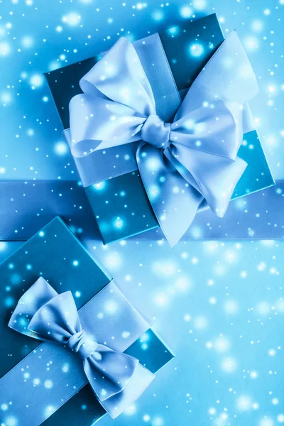 Téli ünnep ajándékok és ragyogó hó a fagyasztott kék háttér, — Stock Fotó