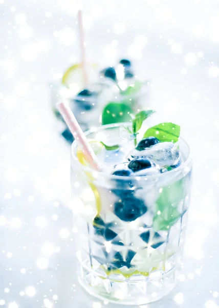 Winter holiday cocktail with ice and glowing snow on background,