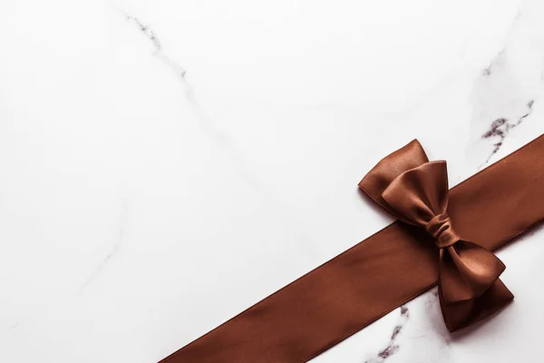 Шоколадно-коричнева шовкова стрічка на мармуровому фоні, плоска — стокове фото