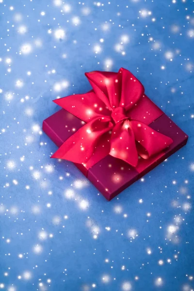 Christmas holiday luxury red gift box on blue background with gl