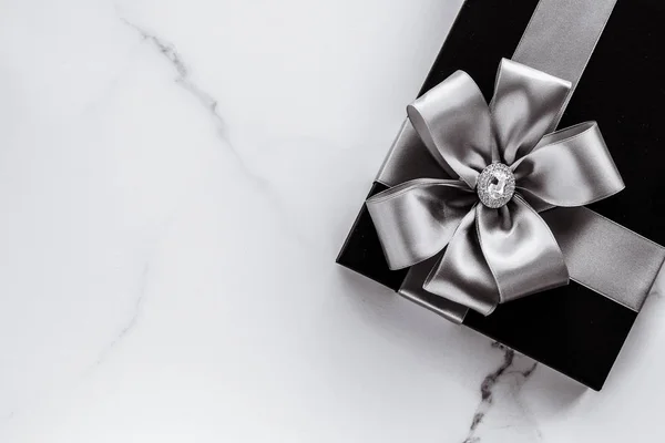Luksusowe prezenty na święta ze srebrną wstążką jedwabiu i kokardą na marmurze b — Zdjęcie stockowe