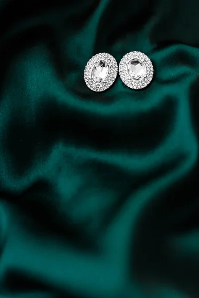 Pendientes de diamantes de lujo en seda verde esmeralda oscura, glamour navideño —  Fotos de Stock