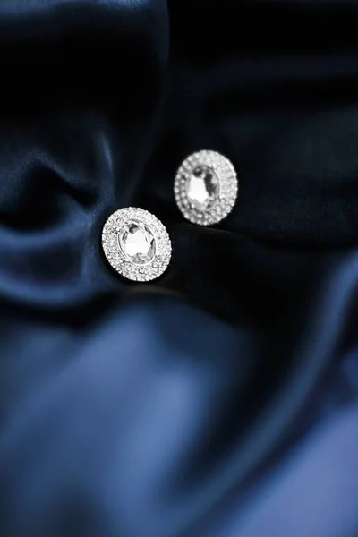 Lyxiga diamantörhängen på mörkblå sidenbakgrund, Holiday gl — Stockfoto