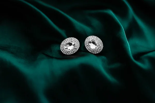 Orecchini di diamanti di lusso su seta verde smeraldo scuro, glam vacanza — Foto Stock