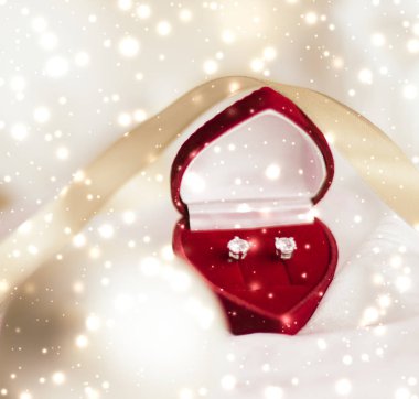 Kalp şeklinde mücevher hediye kutusunda elmas küpe, aşk pres