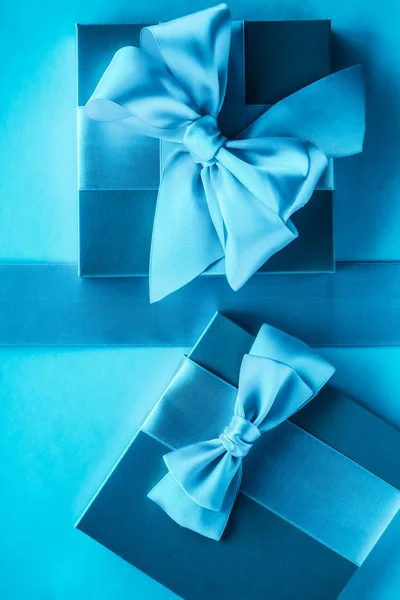 Luxe vakantie geschenken met satijnen lint en strik op blauwe achtergrond — Stockfoto