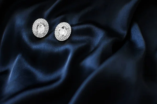 Pendientes de diamantes de lujo sobre fondo de seda azul oscuro, gl vacaciones —  Fotos de Stock