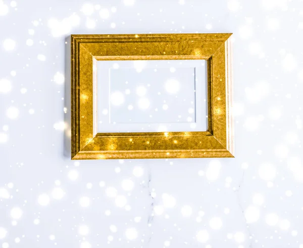 Golden photo frame and glowing glitter snow on marble flatlay ba — Stock Photo, Image