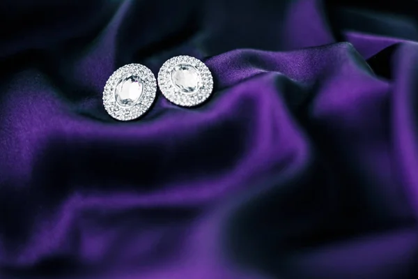 Lyxiga diamantörhängen på mörkt violett sidentyg, Holiday Glam — Stockfoto