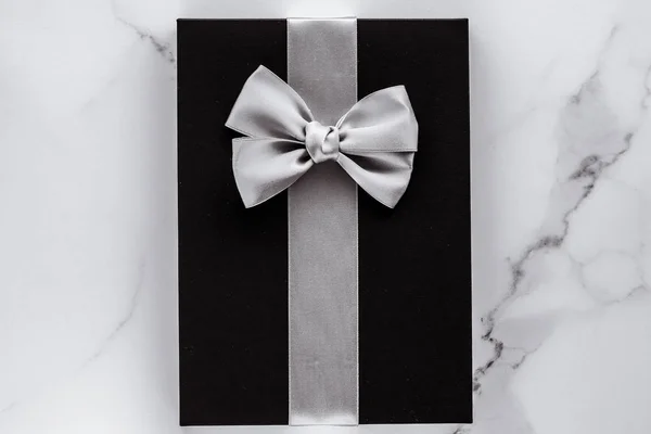 Luxusní sváteční dary se stříbrnou hedvábnou stuhou a lukem na mramorové b — Stock fotografie