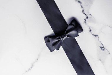 Siyah ipek kurdele ve yay mermer arka planda, yatık