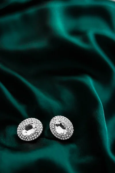 Luxusní diamantové náušnice na tmavě smaragdově zeleném hedvábí, sváteční glám — Stock fotografie