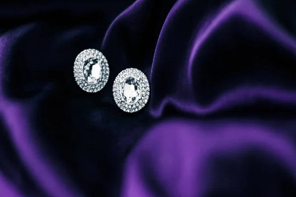 Pendientes de diamantes de lujo en tela de seda violeta oscura, glam navideño —  Fotos de Stock