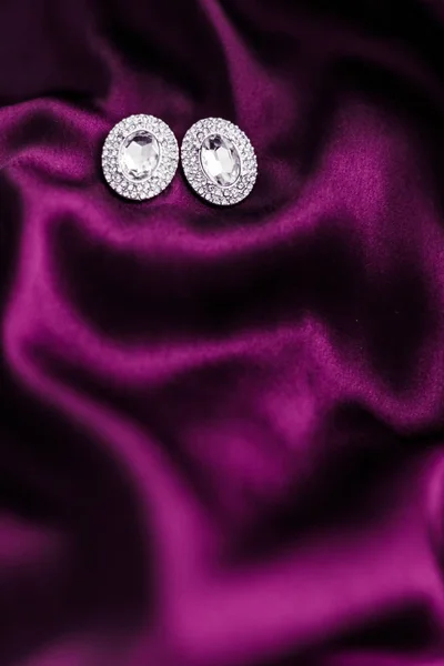 Luxe diamanten oorbellen op donker roze zijde stof, vakantie portret Rechtenvrije Stockfoto's